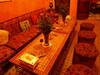 a living room with two tables and chairs and a tableasteryasteryasteryasteryastery at Riad Anass Al Ouali in Fès