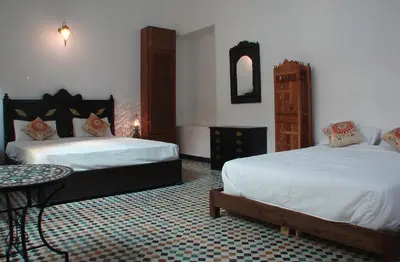 a hotel room with two beds and a table at Riad Sheryne Fes in Fès