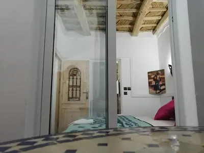 a bedroom with a glass door and a bed at Riad Bleu Afriqua in Boumalne