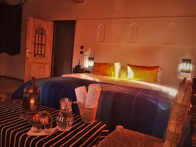 a bedroom with a large bed and a table with a table sidx sidx at Riad Bleu Afriqua in Boumalne