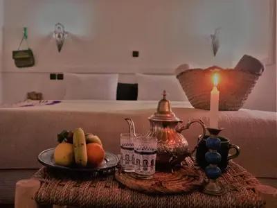a table with a plate of fruit and a candle at Riad Bleu Afriqua in Boumalne