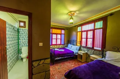 a bedroom with two beds and a bathroom at Les Jardins De Todgha gorges de todra tinghir in Aït Baha