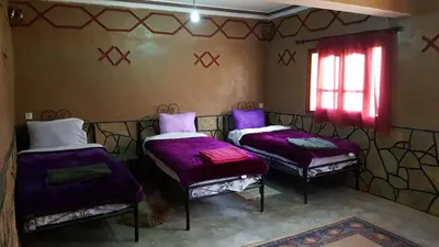 two beds in a room with purple sheets and a window at Les Jardins De Todgha gorges de todra tinghir in Aït Baha