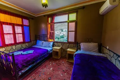 two beds in a room with colorful windows at Les Jardins De Todgha gorges de todra tinghir in Aït Baha