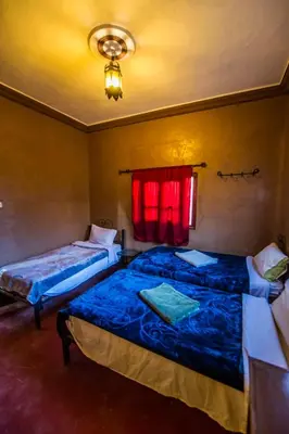 two beds in a room with a red window at Les Jardins De Todgha gorges de todra tinghir in Aït Baha