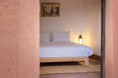 a bed with white sheets and a picture on the wall at Ecolodge Quaryati Marrakech in Douar Tounsi