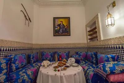 a room with a table with a cat sitting on a couch at Riad Jardin Chrifa in Fès