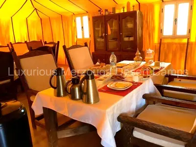 a table with utensils on it in a tent at Luxurious Merzouga Desert Camps in Merzouga