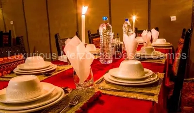 a table with white hats and plates on it at Luxurious Merzouga Desert Camps in Merzouga