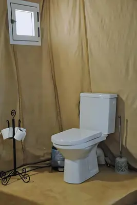a white toilet in a room with a window at Luxurious Merzouga Desert Camps in Merzouga