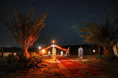 a starry night with two people walking down a path at Luxurious Merzouga Desert Camps in Merzouga