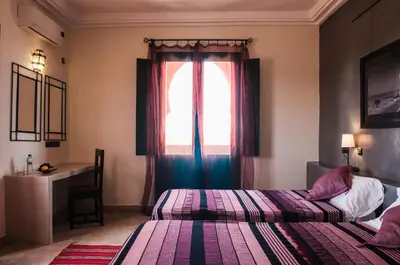 a hotel room with two beds and a window at Dar Chamaa in Ouarzazate