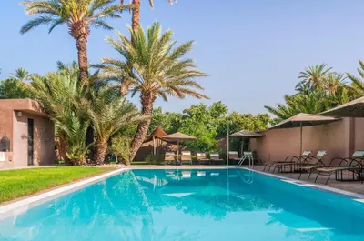 a swimming pool with palm trees in the background at Dar Chamaa in Ouarzazate