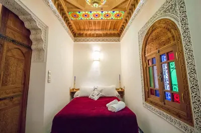 a bedroom with a red bed with a stained glass window at Dar Mfaddel in Fès