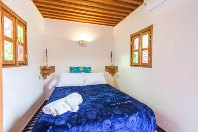 a bedroom with a blue bed with two windows at Dar Mfaddel in Fès