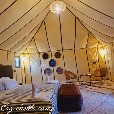 a tent with two people laying on a bed at Erg Chebbi Camp in Merzouga