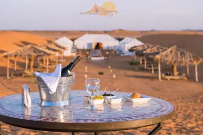 a table in the desert with food and drinks on it at Erg Chebbi Camp in Merzouga