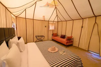 a tent bedroom with a bed with a hat on it at Erg Chebbi Camp in Merzouga