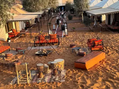 a group of tables and chairs in the sand at Erg Chebbi Camp in Merzouga