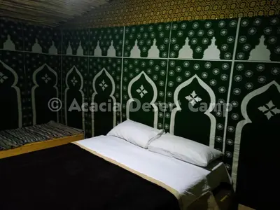 a bedroom with a bed with a black and white wallpaper at Acacia Desert Camp in Merzouga