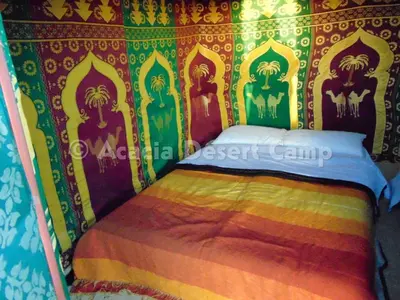a bed in a room with a colorful wall at Acacia Desert Camp in Merzouga