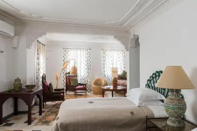 a bedroom with a bed and a living room at Riad Jardin Des Biehn in Fès