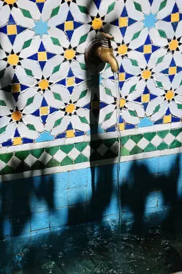 a bathroom with a water faucet and a mosaic wall at Riad Jardin Des Biehn in Fès