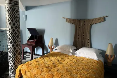 a bedroom with a bed with a orange blanket and pillows at Riad Jardin Des Biehn in Fès