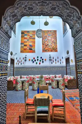 a room with tables and chairs and a painting on the wall at Dar Fes Tresor in Fès
