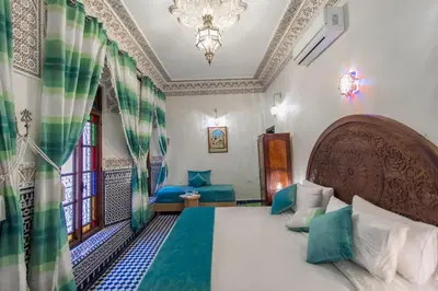 a bedroom with a bed and a chandelier at Dar Fes Tresor in Fès