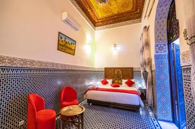 a bedroom with a bed and two red chairs at Dar Fes Tresor in Fès