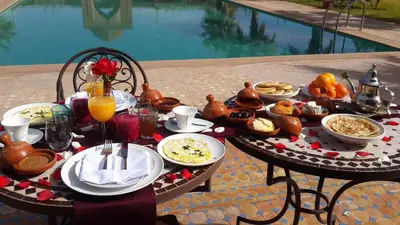 a table with food and drinks on it next to a pool at Kasbah ATFEL in Ourika
