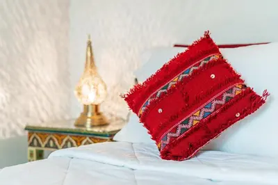 a red pillow sitting on top of a bed at Riad Taj Salma in Fès