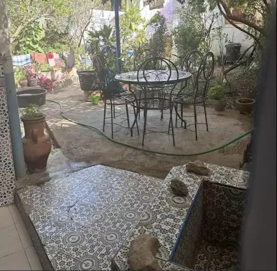 a patio with a table and chairs in a yard at Le jardin d'habiba in Rhorm el Alem