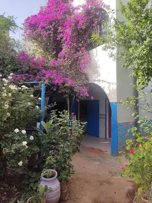 a blue and white building with a bunch of flowers at Le jardin d'habiba in Rhorm el Alem