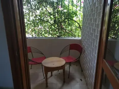 a porch with two chairs and a table and a window at Le jardin d'habiba in Rhorm el Alem