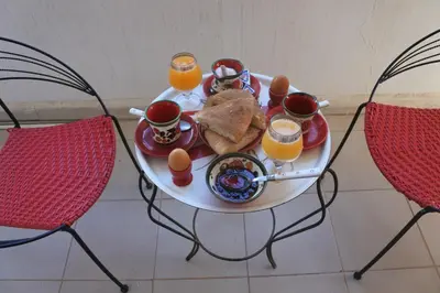 a table with a tray of food and two glasses of orange juice at Le jardin d'habiba in Rhorm el Alem