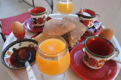 a plate of breakfast food with eggs and orange juice at Le jardin d'habiba in Rhorm el Alem