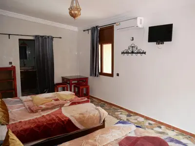 a bedroom with two beds and a flat screen tv at Hotel Baddou in Tamtetoucht