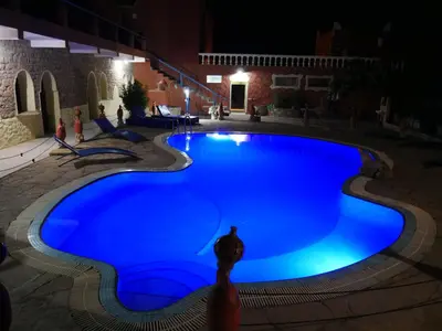 a large blue swimming pool at night at Hotel Baddou in Tamtetoucht