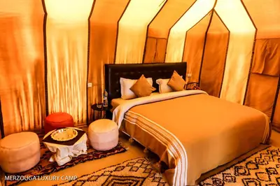 a bedroom with a large bed and a table at Merzouga Luxury Bivouac in Merzouga