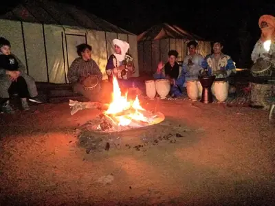 a group of people sitting around a fire at Merzouga Luxury Bivouac in Merzouga