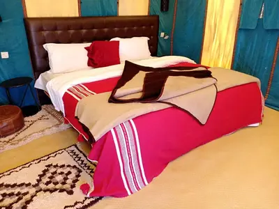 a bedroom with a bed with a red and white blanket at Merzouga Luxury Bivouac in Merzouga