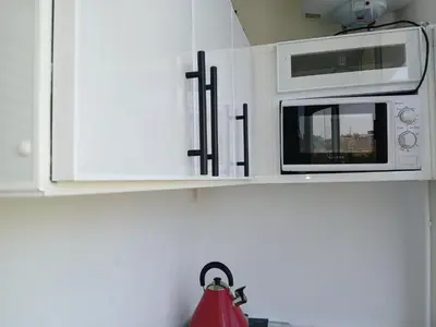 a kitchen with white cabinets and a microwave at Ryan S3 in Fès