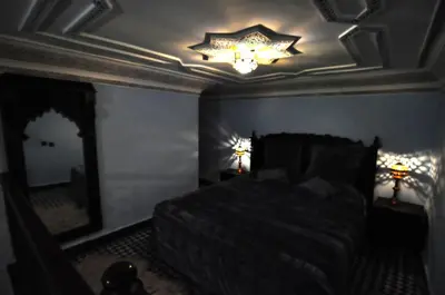 a bedroom with a bed and a ceiling with a chandelier at Riad Khouloud in Fès