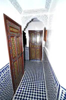 a hallway with two wooden doors and a checkered floor at Riad Khouloud in Fès