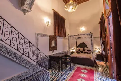 a bedroom with a bed and a staircase with a mirror at Riad Naila & suite in Fès