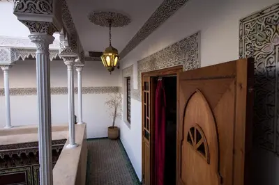 a hallway with a bed and a wooden door at Riad Naila & suite in Fès