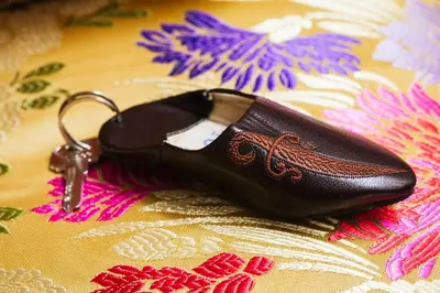 a pair of black shoes with a key on a blanket at Riad Naila & suite in Fès
