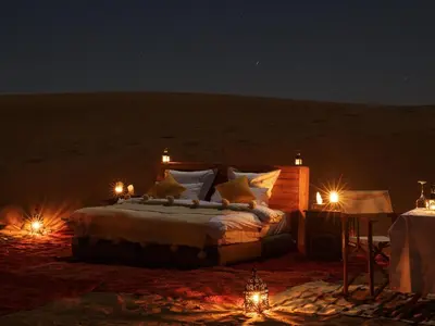 a bed in the middle of the desert at night at Nubia Luxury Camp Erg Chegaga in El Gouera